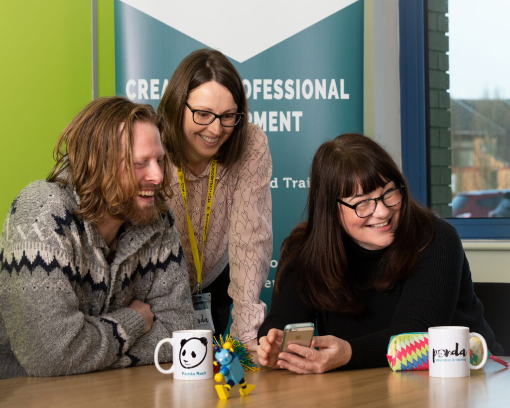 Trainer working with students in a workshop with Panda mugs on the table.
