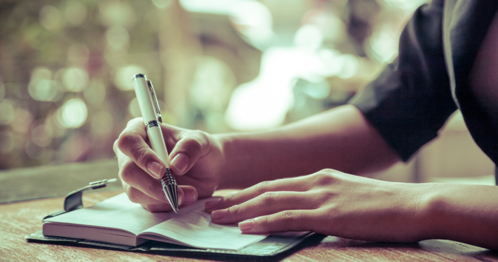 A female carrying out reflective practice through writing in a notebook
