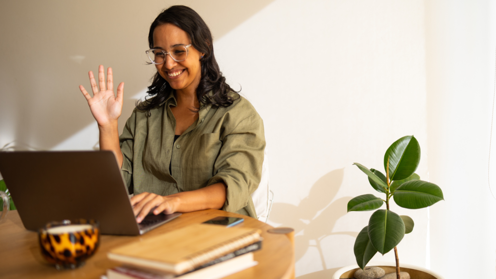 A young lady in her early 30s looking at her lap top screen happily as she waves goodbye to her assessor. Learner motivation was successful here!